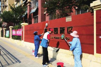 高家园新区创城志愿者在清洗小区大门围墙。